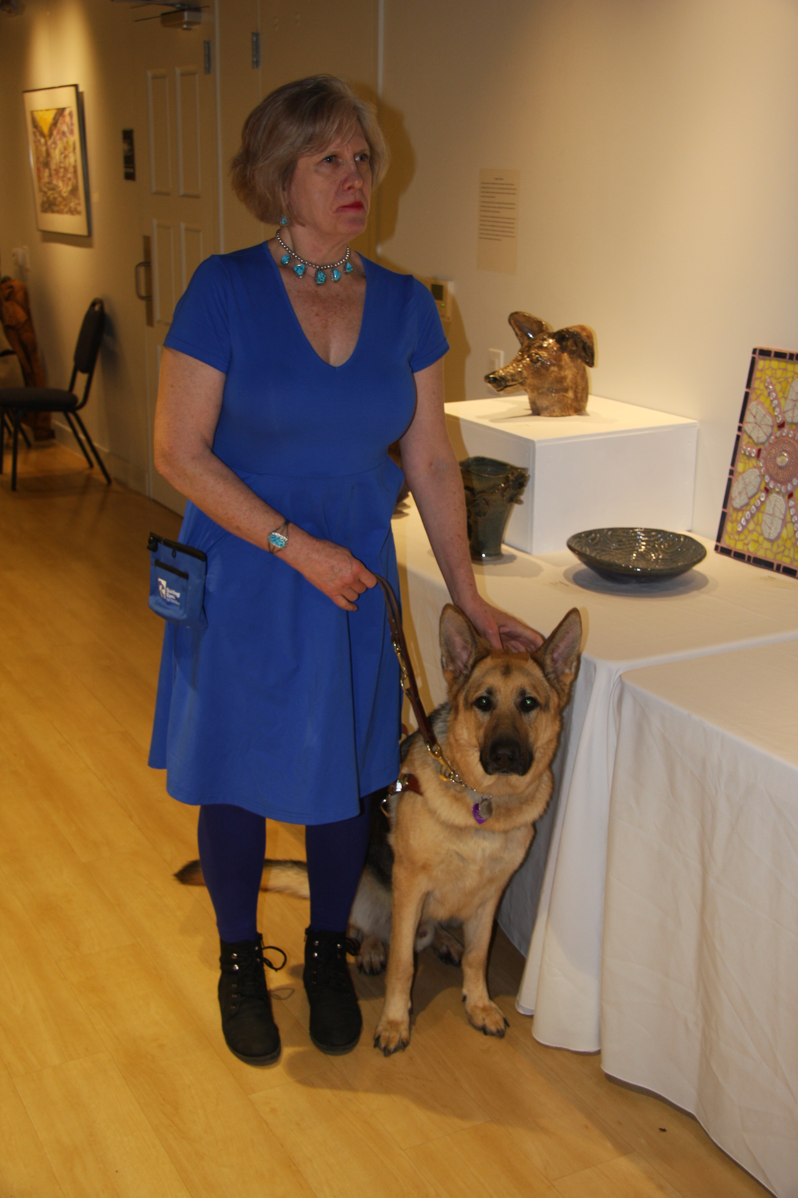 Angela and her guide dog Rajah in front of some of her artwork 